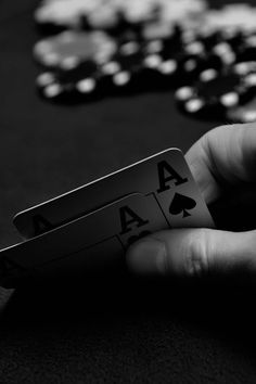 a hand holding playing cards in front of some casino chips on a table with other poker chips