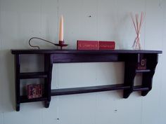 a shelf with candles and books on it next to a wall mounted candle holder in the corner