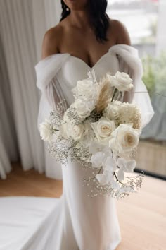 a bride holding a bouquet of white flowers