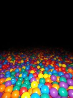 many colored balls are scattered on the floor in an indoor play area at night time