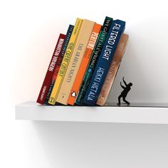 a small figurine is standing on top of a book shelf next to several books