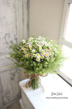 a bouquet of daisies is sitting on a window sill