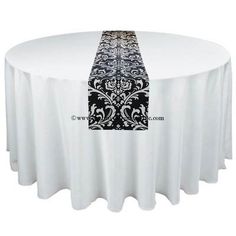 a round table with a black and white damask design on the top, along with a matching runner