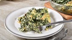 a white plate topped with spinach casserole next to a bowl of broccoli