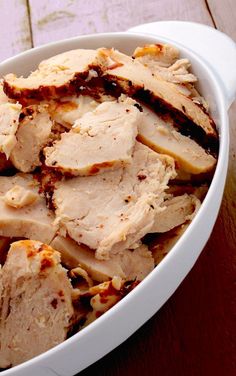 a white bowl filled with sliced meat on top of a wooden table