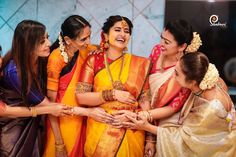 a group of women standing next to each other wearing different colored sari and jewelry