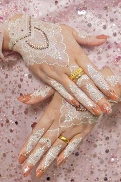 two hands with white and gold manies on top of each other's fingers