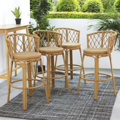 four wicker bar stools and a table on a rug