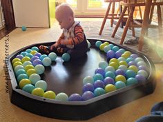 a baby sitting on top of a play mat with balls in the shape of a heart