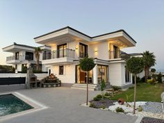 a large white house sitting on top of a lush green field next to a swimming pool