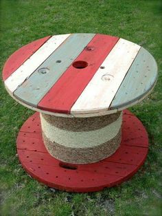 a red, white and blue striped wooden table on top of a green grass covered field