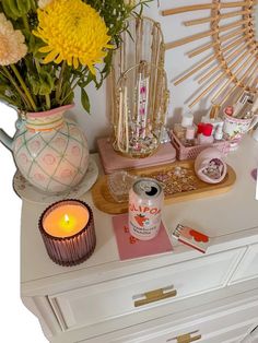 a white dresser topped with lots of different types of items and flowers on top of it