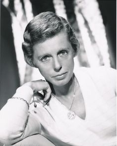 an old black and white photo of a woman with her hand on her chin, looking at the camera