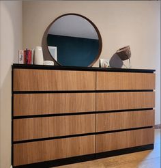 a dresser with a mirror on top of it next to a wall and hardwood floor