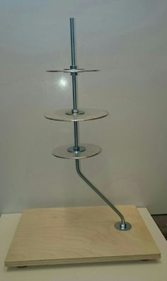 a three tiered shelf on top of a wooden board with a metal hook in the middle