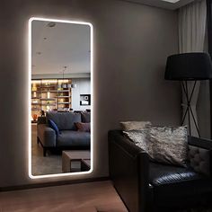 a living room filled with furniture and a large lighted mirror on the wall above it