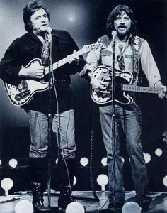 two men on stage with guitars and microphones