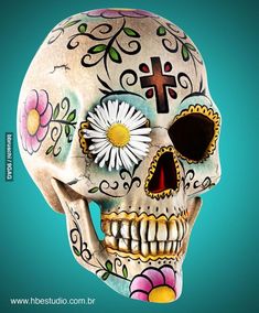 a skull with flowers painted on it's face and cross in the center, against a blue background