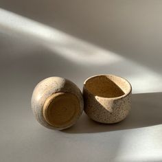 two ceramic bowls sitting side by side on a white surface, one has a shadow from the window