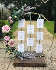 a wooden table with flowers and place cards on it in front of a brick walkway