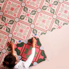 a woman is laying on the floor with her hands up to paint a wallpaper design