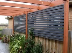 an outdoor area with wooden fence and plants on the side of the building, along with brick walkway