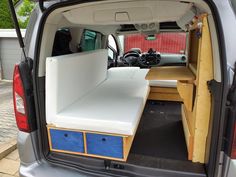 the back end of a van with an open hatchback door and storage drawers in it