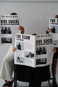 two women sitting in chairs holding up newspapers with the same image on them and one reading