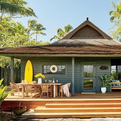 a magazine cover with a house and surfboard on the front porch, surrounded by palm trees