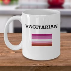 a white coffee mug with the words vagitrian on it sitting on a wooden table