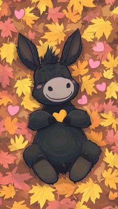 a black stuffed animal sitting on top of leaves in the fall with hearts drawn on it's chest