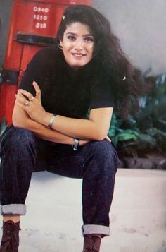 a woman sitting on the ground in front of a red phone booth with her arms crossed