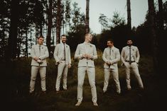 a group of men standing next to each other in front of some tall pine trees