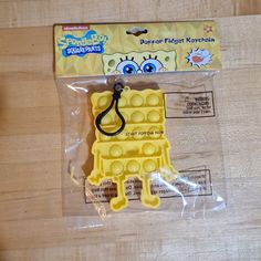 a yellow lego keychain sitting on top of a wooden table next to a packaged package