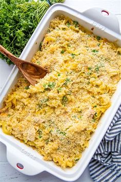 a casserole dish with broccoli in it and a wooden spoon on the side