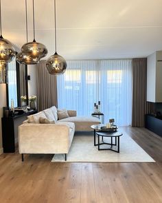 a living room filled with furniture next to a large window covered in curtains and lights