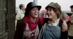 two young women walking down the street with one holding her arm around the other's shoulder