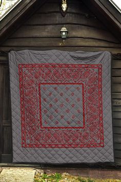 a quilt hanging on the side of a wooden building in front of a light pole