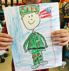 a child holding up a drawing of a man in green and red uniform with an american flag on it