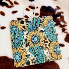 an animal print purse with sunflowers and cactuses on the front, sitting on a cowhide surface