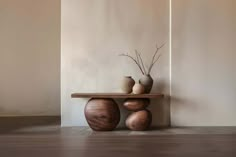 two vases sitting on top of a wooden table in front of a white wall