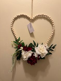 a heart shaped wreath with flowers hanging on the wall