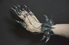 a woman's arm with black and silver jewelry on it, including an elaborate bird bracelet