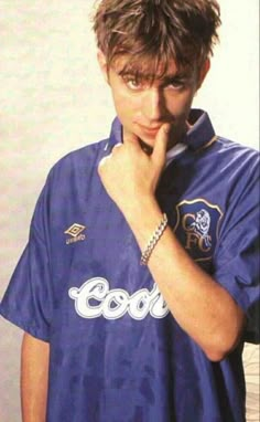 a young man is posing with his hand on his face and wearing a shirt that says cool