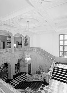 an old black and white photo of a staircase in a large room with checkered flooring