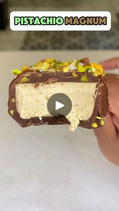 a person holding a piece of cake with chocolate and candy toppings on it's side