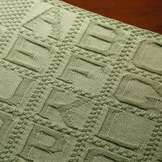 a green knitted blanket sitting on top of a wooden table