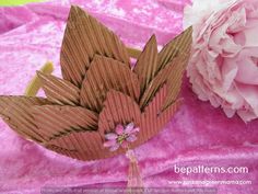 a pink flower sitting on top of a table next to a piece of cardboard paper