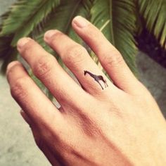 a person's hand with a small horse tattoo on the middle of their finger