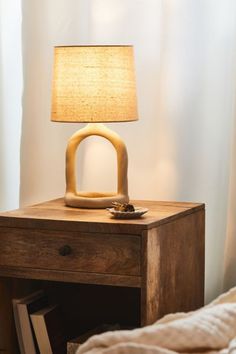 a nightstand with a lamp on it next to a bed